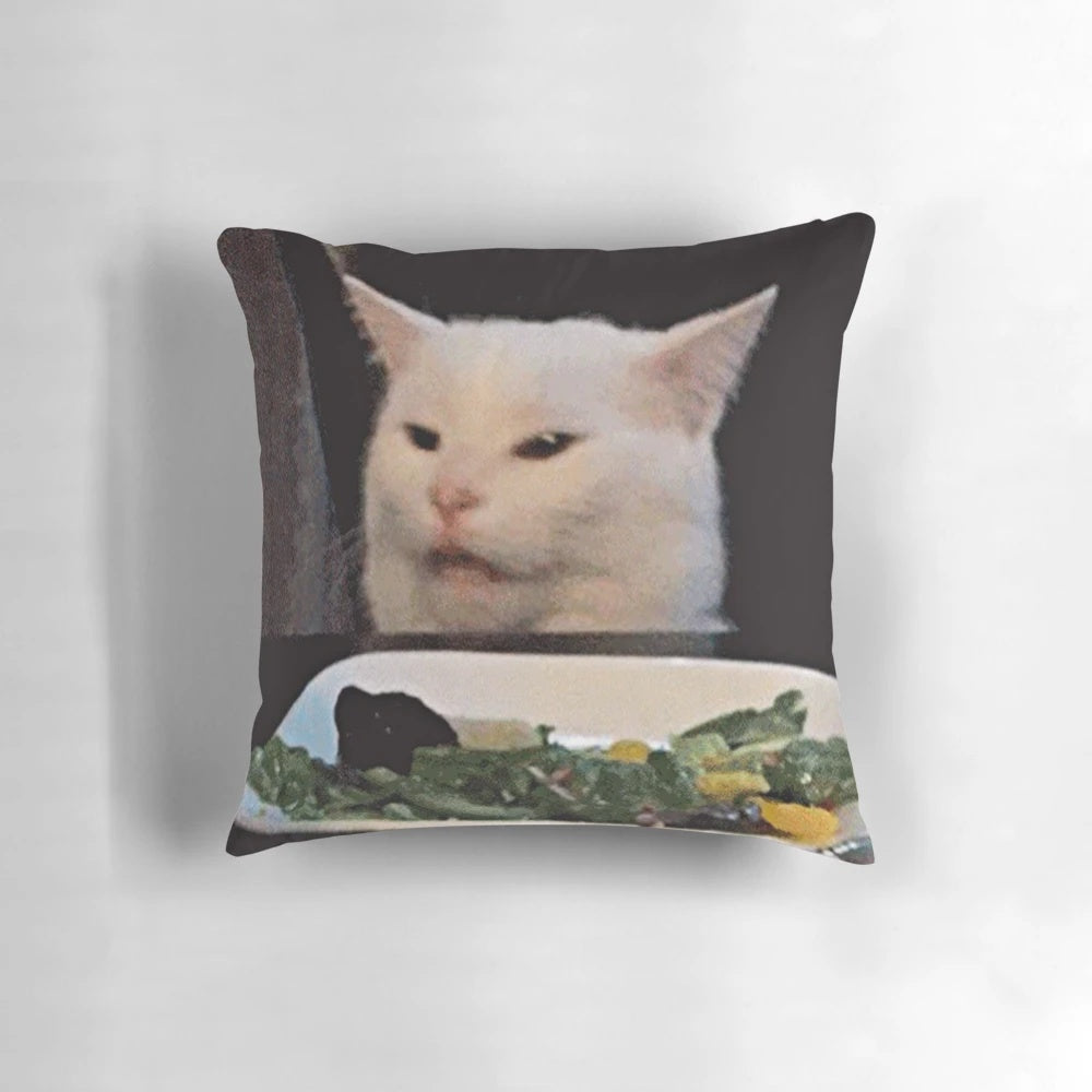 Pillow with image of woman shouting at a confused cat sitting on a table