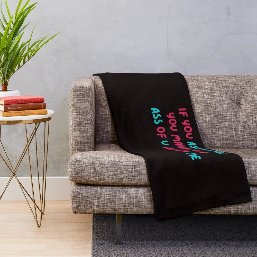Plush blanket with the phrase "If you assume, you make an ASS of U and ME" against a black background