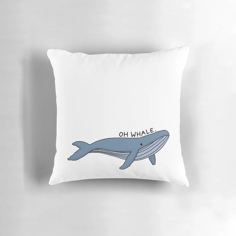 A decorative throw pillow featuring a whimsical illustration of a humpback whale with the text "Oh Whale" in a stylized calligraphy-inspired font.