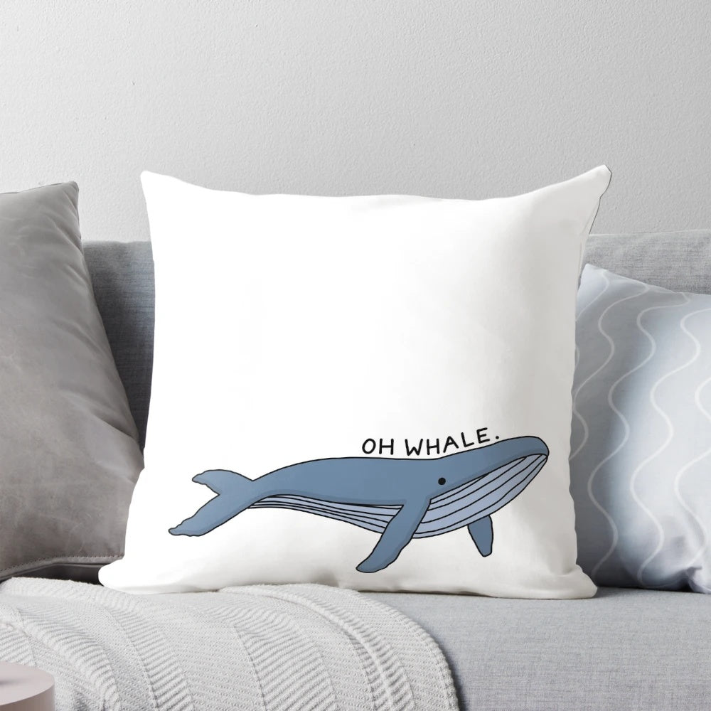 A decorative throw pillow featuring a whimsical illustration of a humpback whale with the text "Oh Whale" in a stylized calligraphy-inspired font.