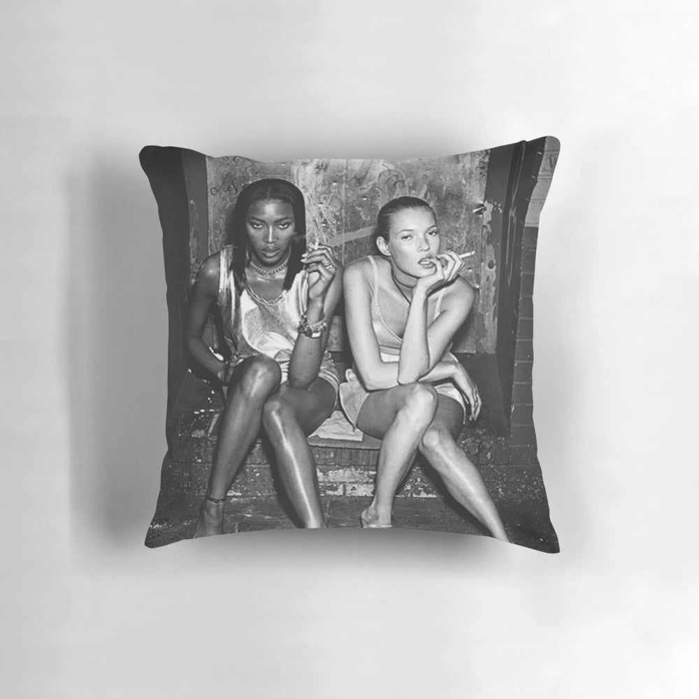 Black and white photograph of 90s supermodels Naomi Campbell and Kate Moss posing together on a pillow.