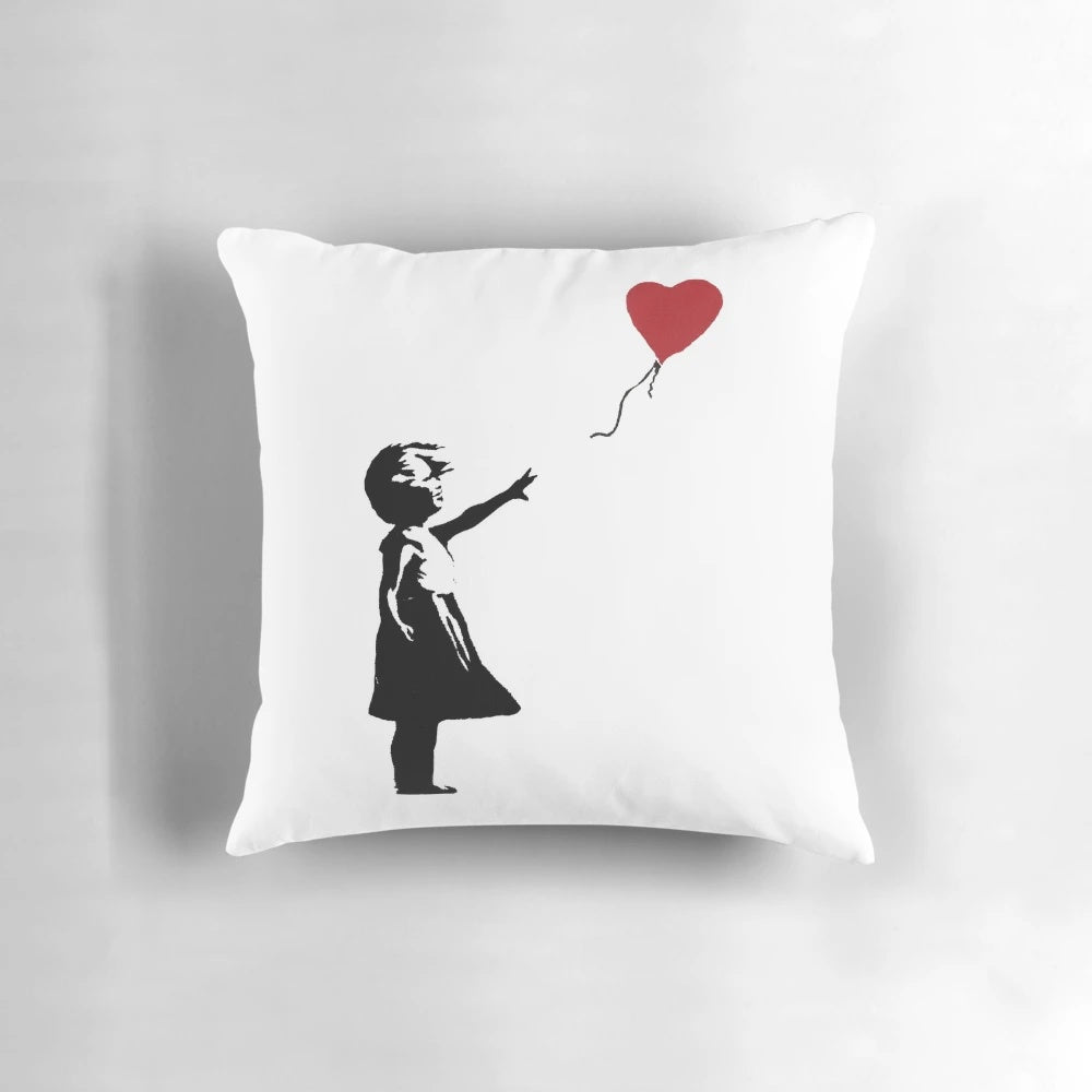 Decorative pillow featuring the iconic Banksy street art image of a girl reaching for a heart-shaped balloon.