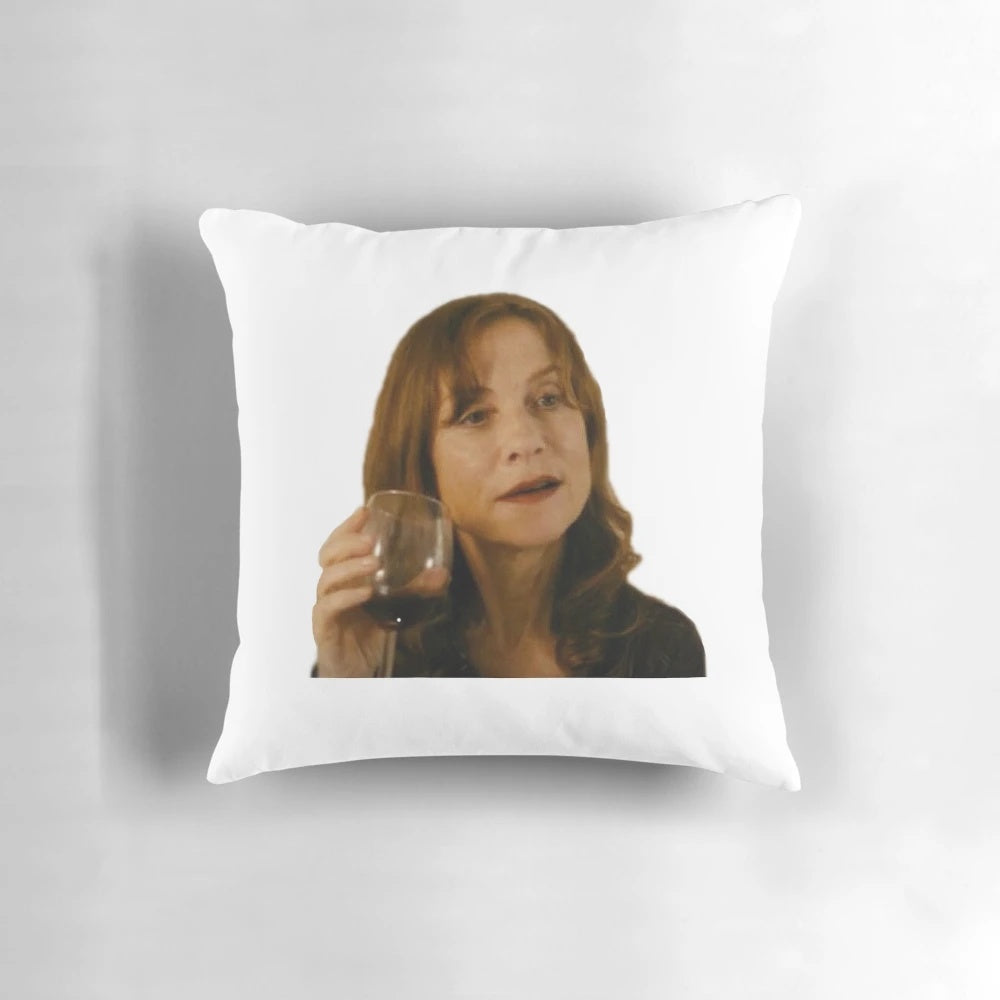 Isabelle Huppert, the renowned French actress, enjoying a glass of wine on a decorative pillow.