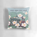A soft, square pillow with an illustration of a baby turtle surrounded by strawberry flowers, with the text "Small Steps Still Count