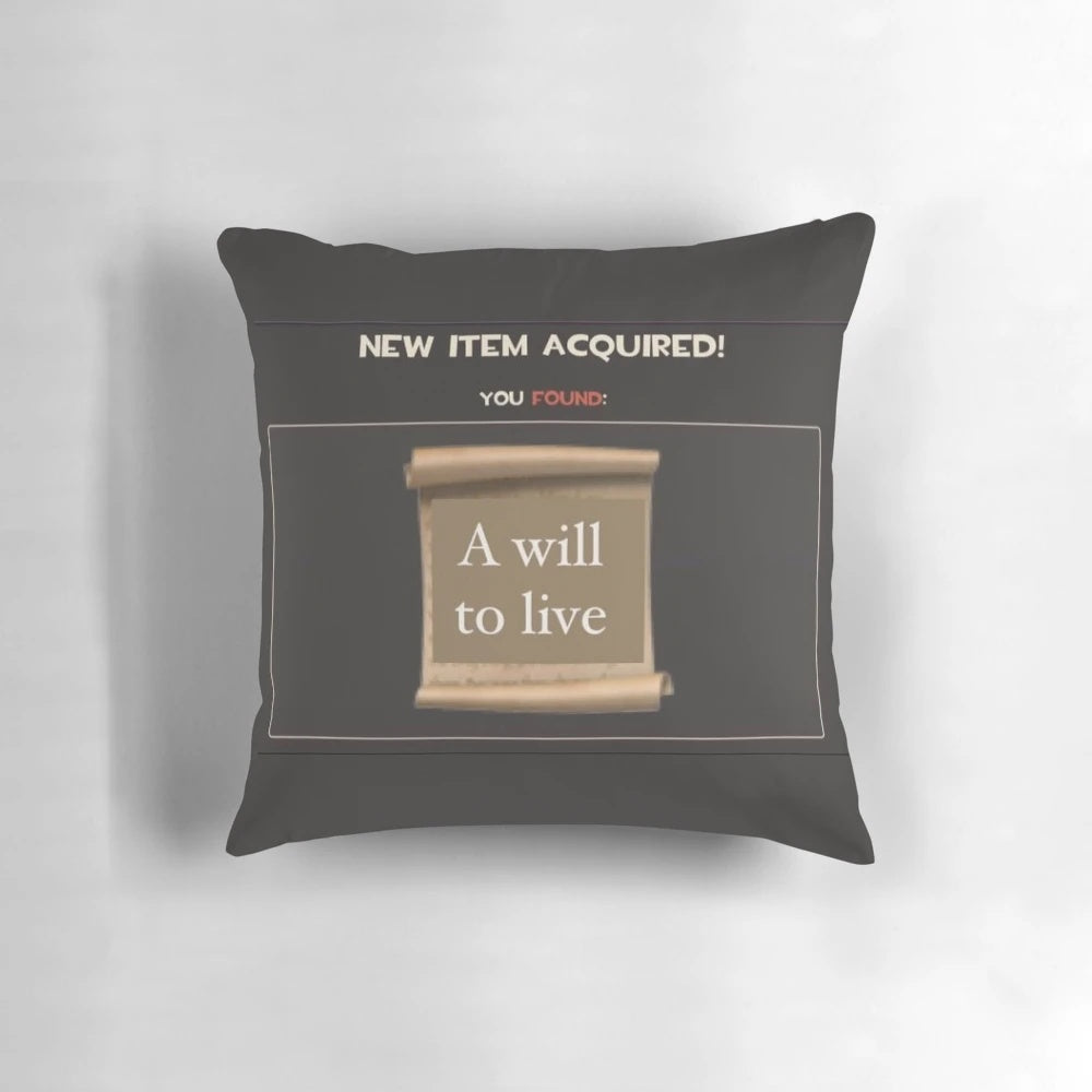 Close-up of a white pillow with the text "Will to Live" printed on it, a design that combines gaming, memes, and inspirational messages.