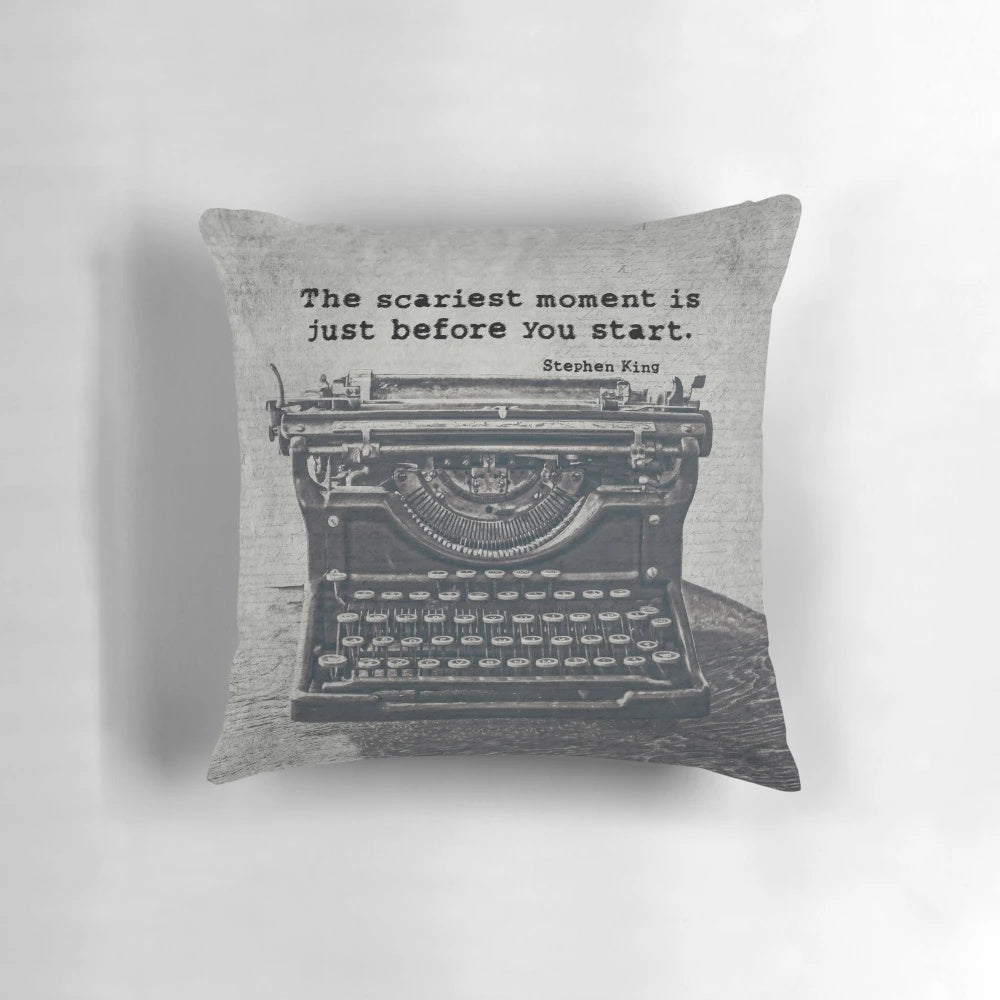 A black and white pillow featuring a vintage typewriter and an inspirational quote about writing by author Stephen King