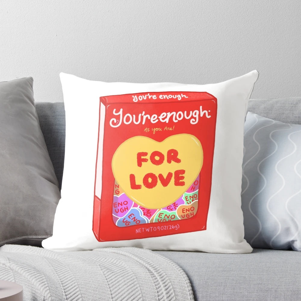 A pink and white 'You're Enough' throw pillow with a whimsical, artsy design to promote mental health and self-love.