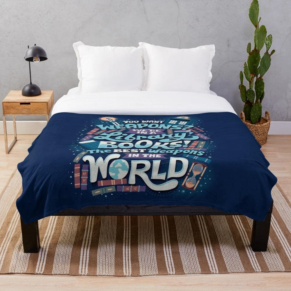 Plush blanket with the phrase "Books are the best weapons" in a stylized, hand-lettered design