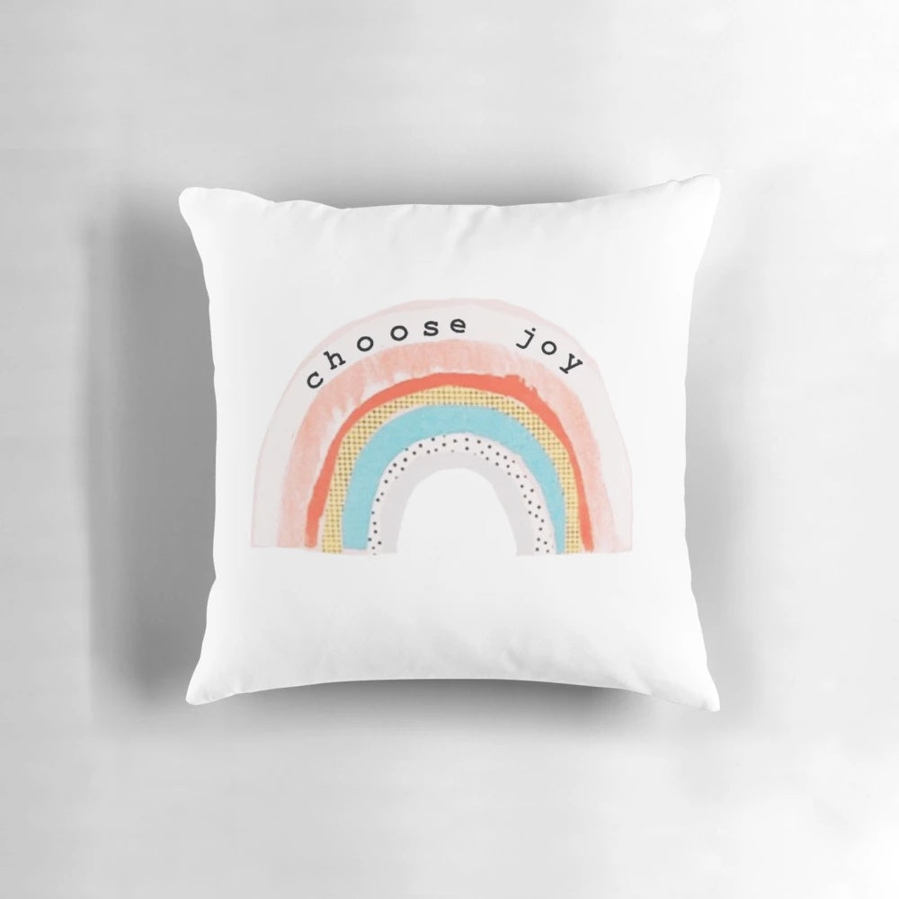 A colorful, decorative pillow featuring a "Choose Joy" design with rainbow colors and polka dots.