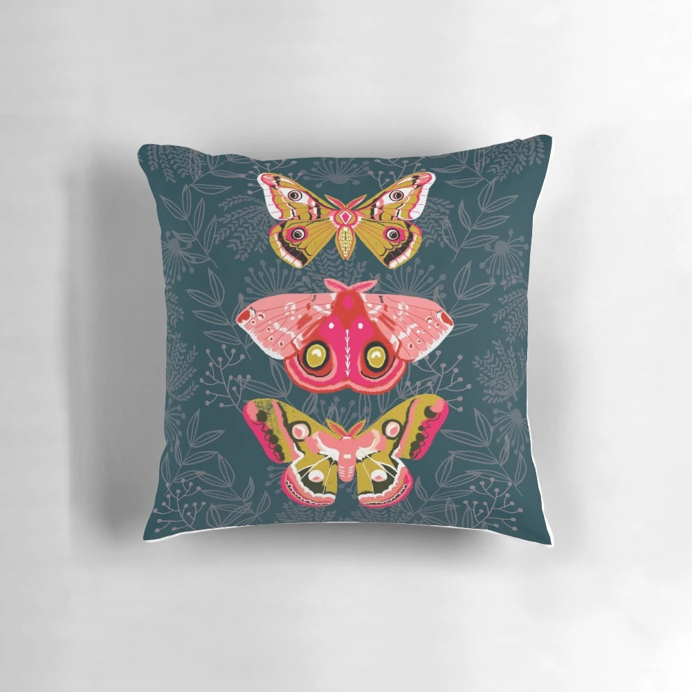 Close-up photograph of a pillow featuring a design of colorful moths and butterflies in a natural, botanical setting.