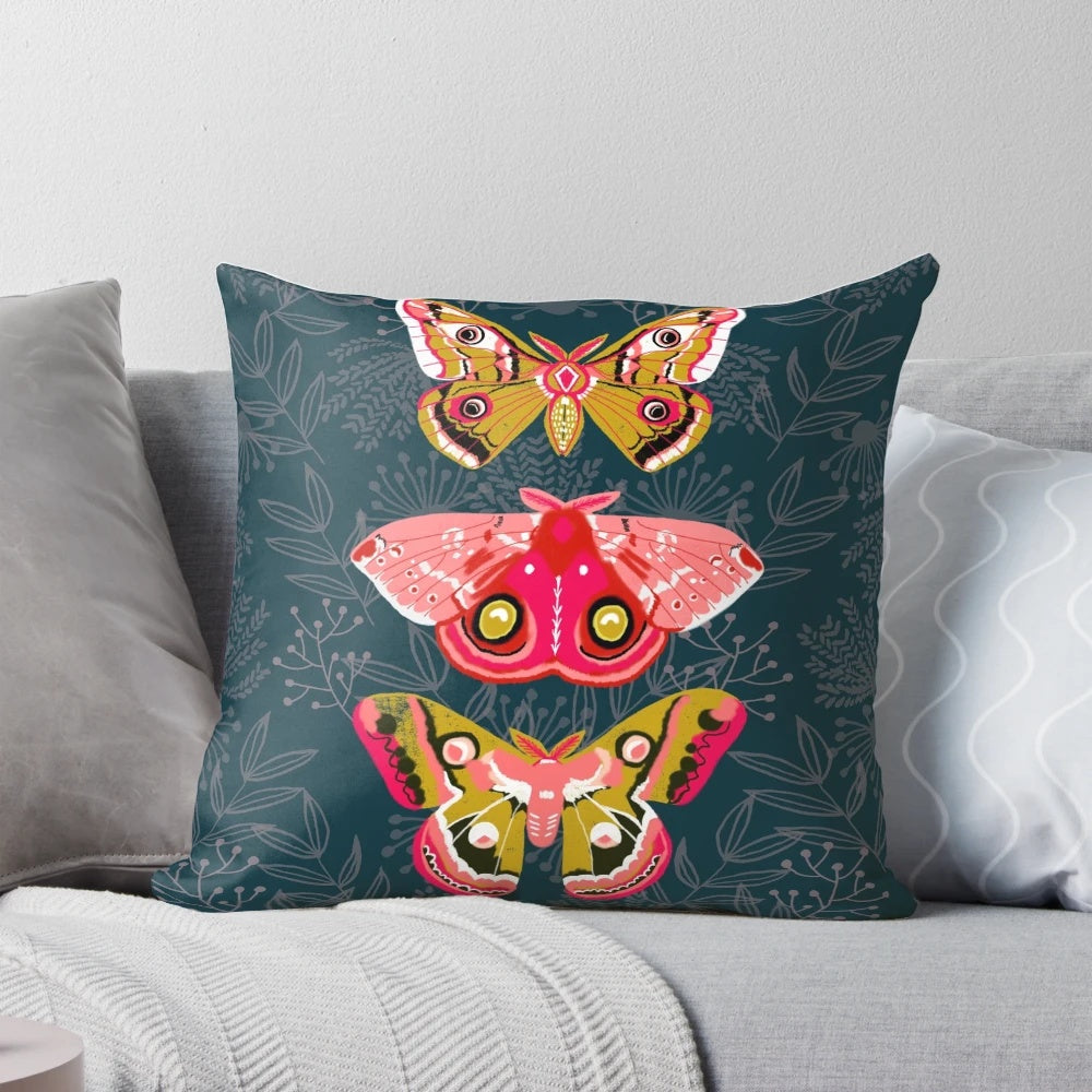 Close-up photograph of a pillow featuring a design of colorful moths and butterflies in a natural, botanical setting.