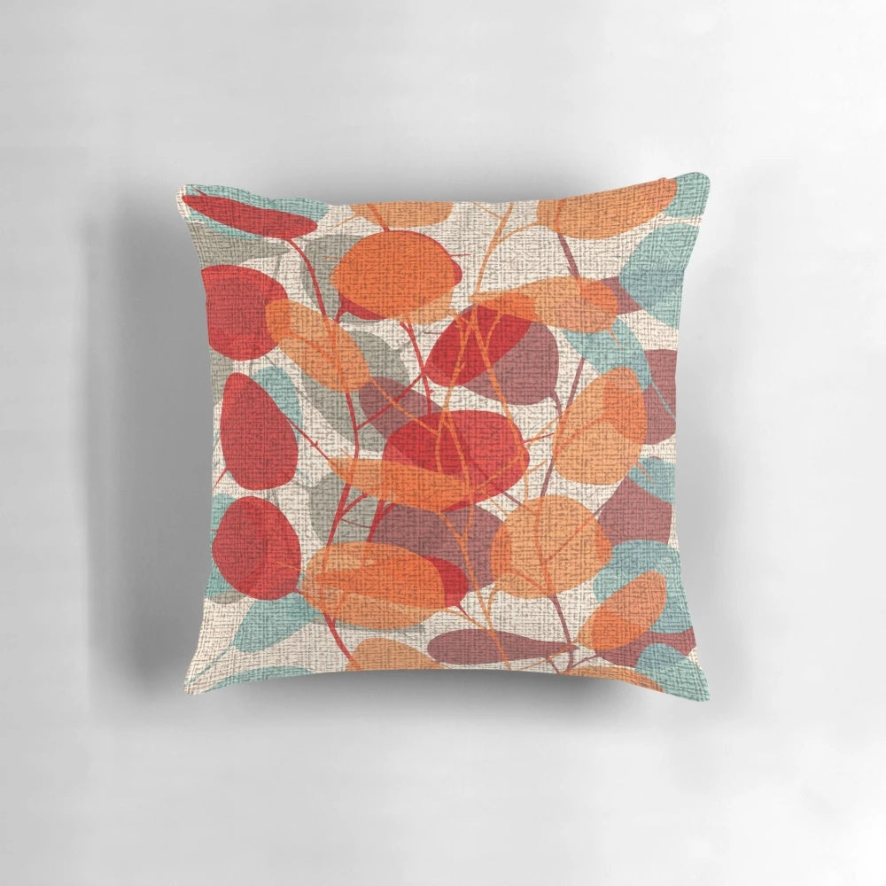 Lunaria Floral Pillow featuring a vibrant mix of red, emerald, and orange leaves against a backdrop of tree branches and silhouettes