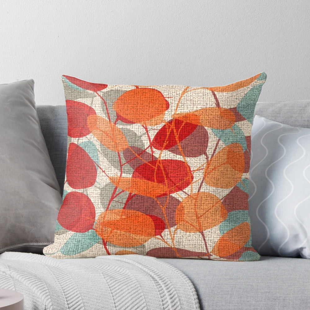 Lunaria Floral Pillow featuring a vibrant mix of red, emerald, and orange leaves against a backdrop of tree branches and silhouettes