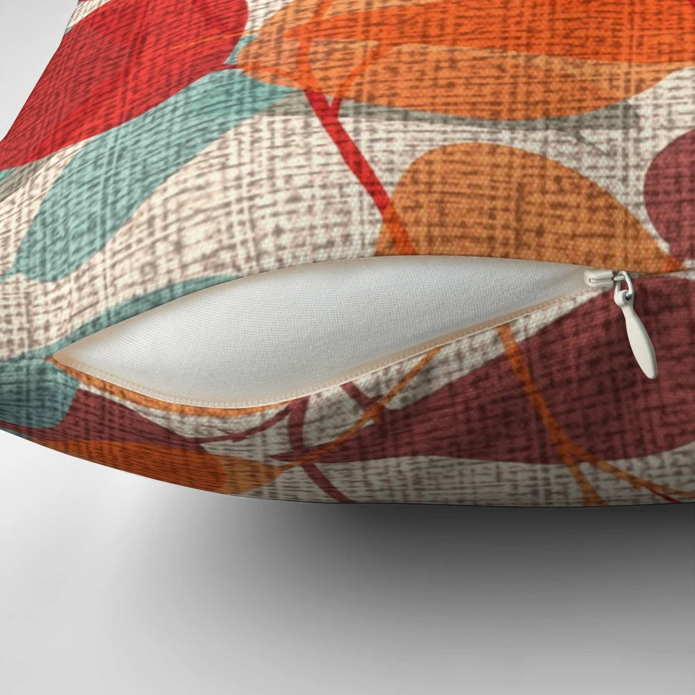 Lunaria Floral Pillow featuring a vibrant mix of red, emerald, and orange leaves against a backdrop of tree branches and silhouettes