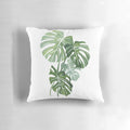 Vibrant watercolor illustration of lush monstera leaves printed on a plush, throw pillow for indoor botanical home decor.