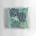 Green monstera leaf printed on a decorative pillow with surreal, tropical vibes