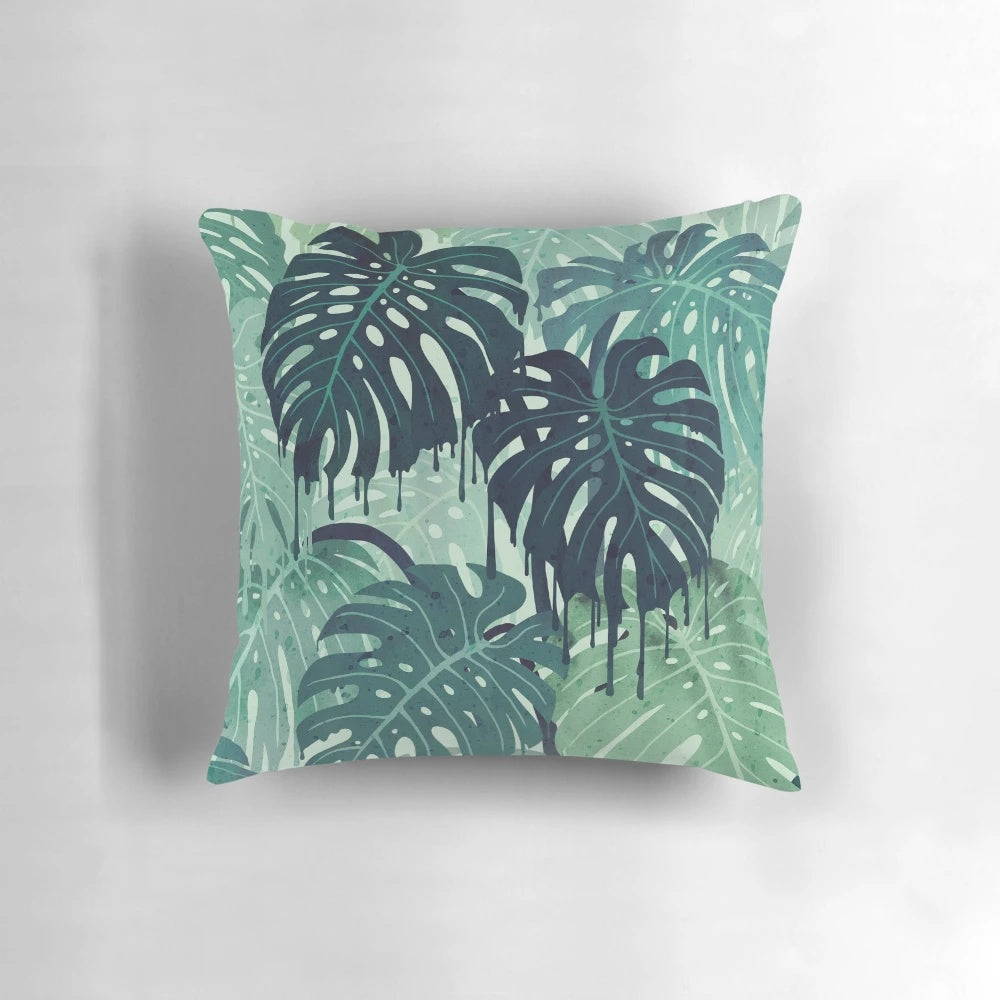 Green monstera leaf printed on a decorative pillow with surreal, tropical vibes