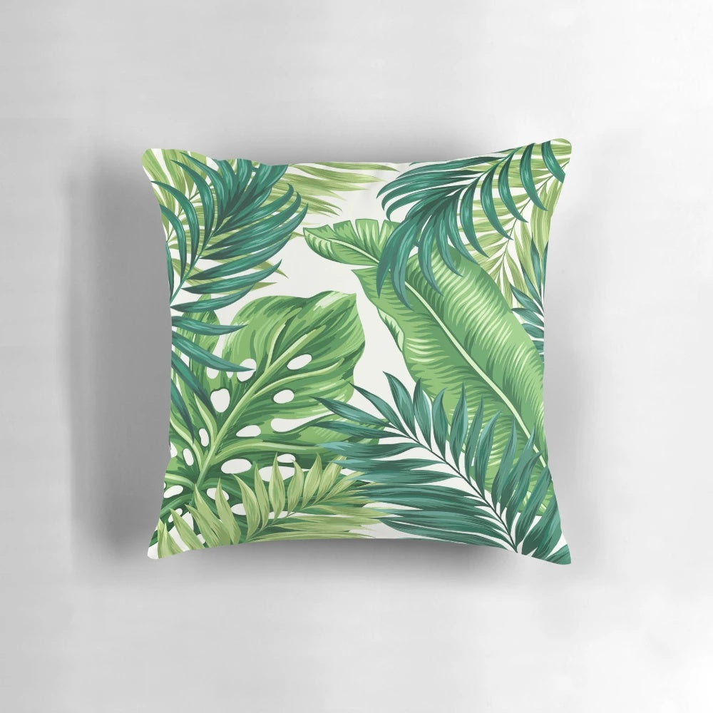 Decorative pillow cover featuring a vibrant print of tropical leaves in shades of green, black, and white.