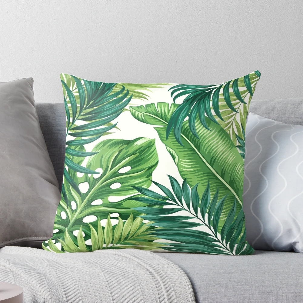 Decorative pillow cover featuring a vibrant print of tropical leaves in shades of green, black, and white.