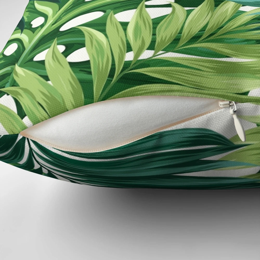 Decorative pillow cover featuring a vibrant print of tropical leaves in shades of green, black, and white.