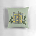 Dark green pillow with gold book illustrations and leaves