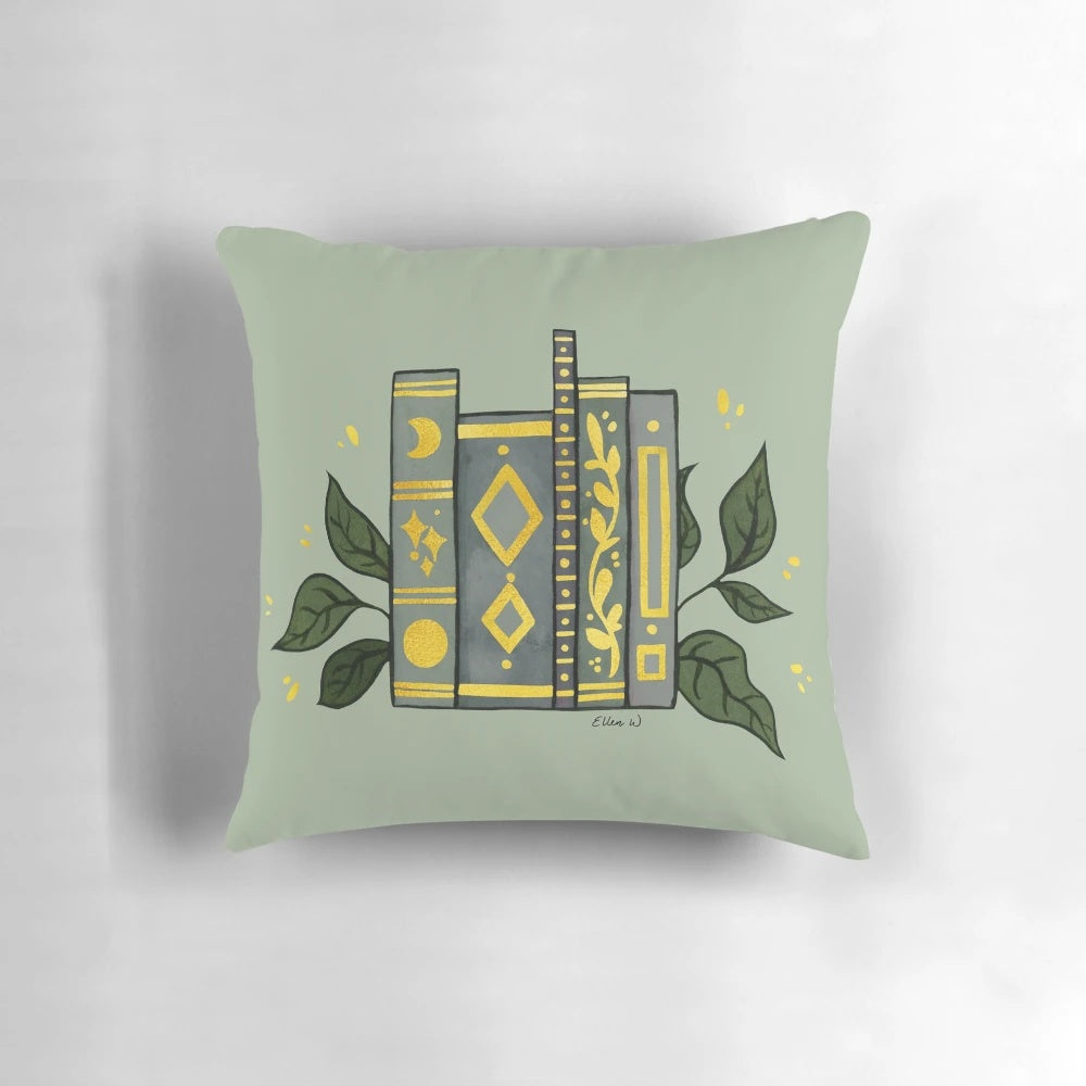 Dark green pillow with gold book illustrations and leaves