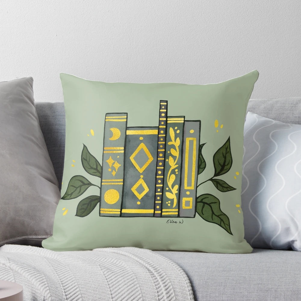 Dark green pillow with gold book illustrations and leaves