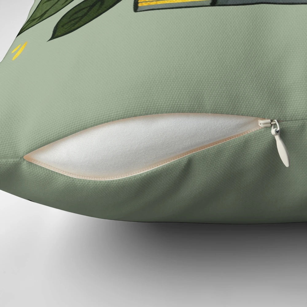 Dark green pillow with gold book illustrations and leaves