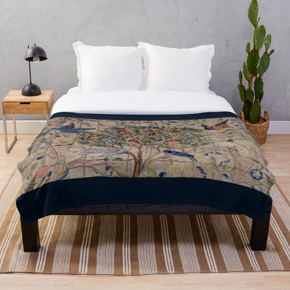 Closeup of a soft, plush blanket featuring a vintage-inspired floral trellis pattern in shades of green, red, and white.
