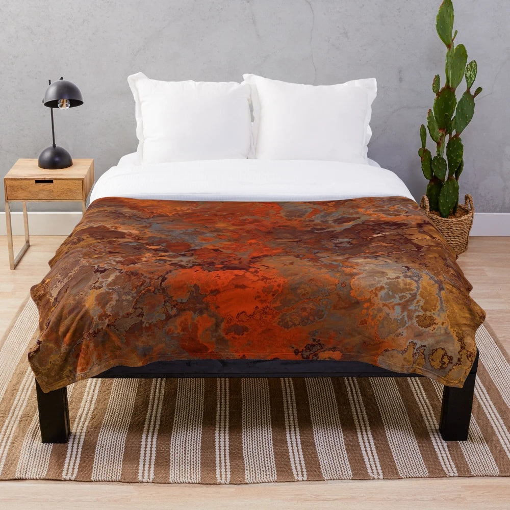 A soft, plush blanket with a metallic gold and rust abstract design