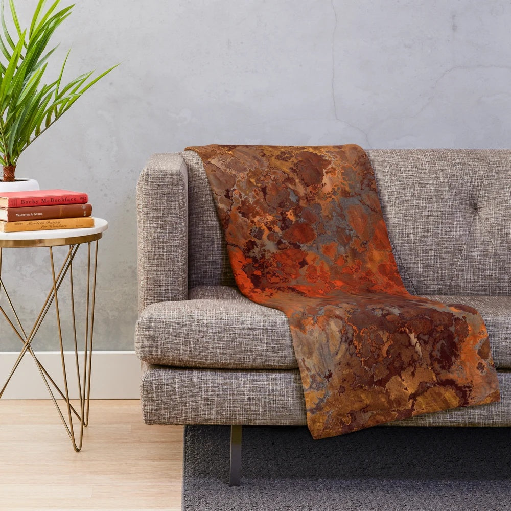 A soft, plush blanket with a metallic gold and rust abstract design