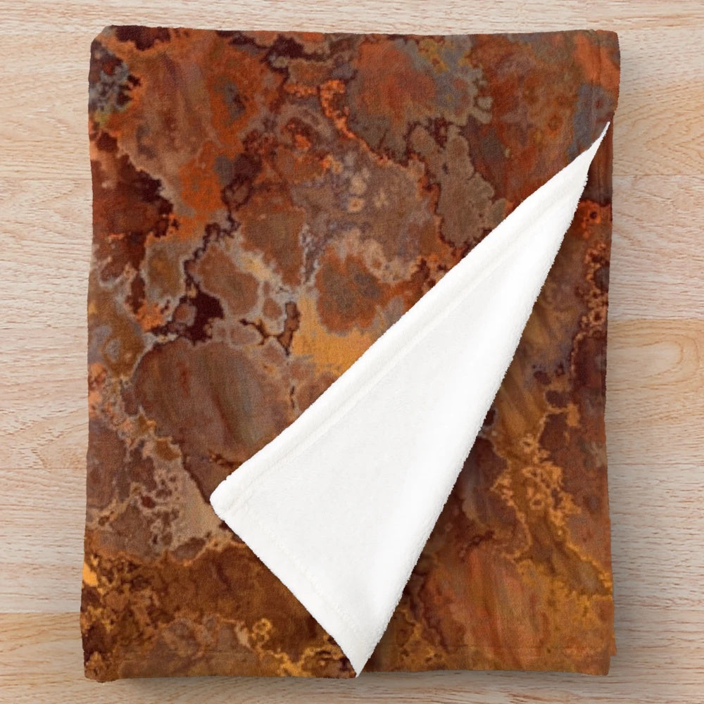 A soft, plush blanket with a metallic gold and rust abstract design
