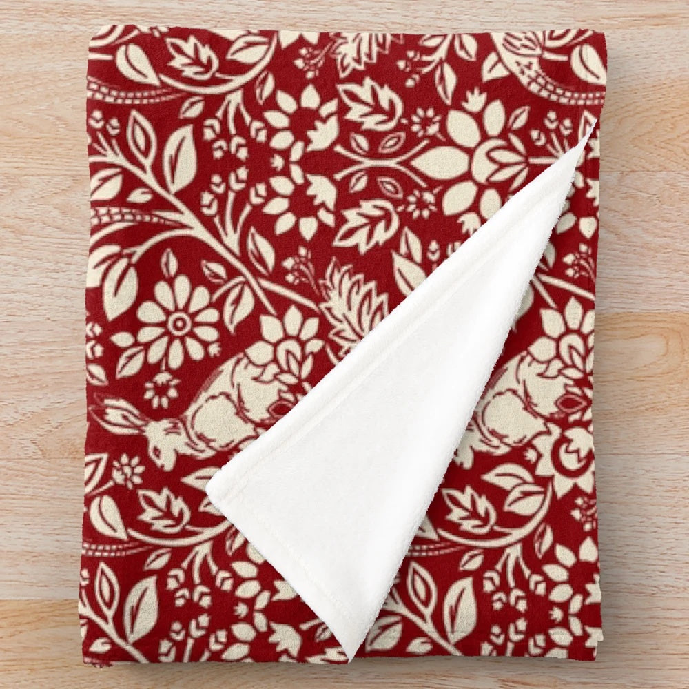 Plush blanket with a vintage-inspired pheasant and hare pattern in deep red and cream colors