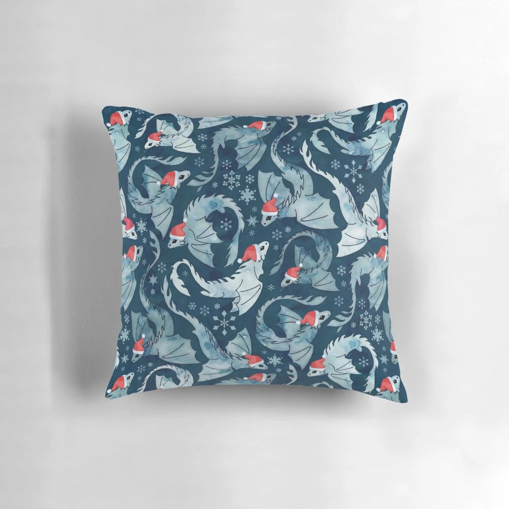 A blue decorative pillow featuring a whimsical dragon surrounded by a watercolor snowflake design, perfect for holiday and winter décor.