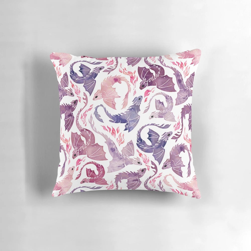 A decorative throw pillow featuring a whimsical, fire-breathing dragon in shades of pink and purple watercolor.