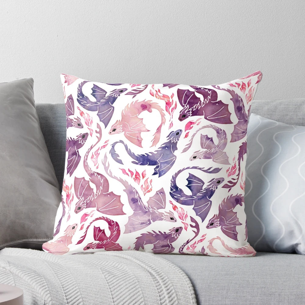 A decorative throw pillow featuring a whimsical, fire-breathing dragon in shades of pink and purple watercolor.