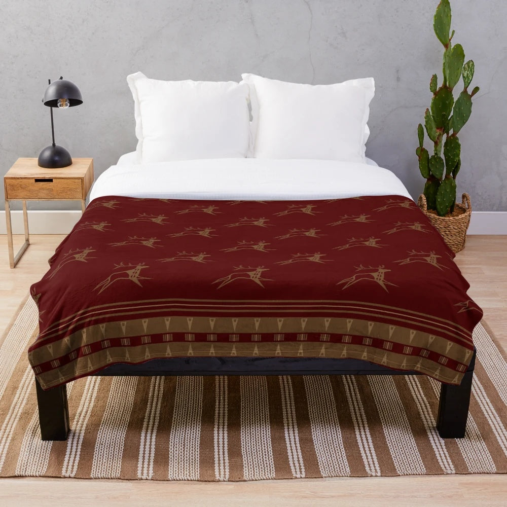 Maroon and gold plush blanket featuring a running elk design, inspired by native american art and wildlife