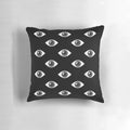 Close-up of a modern, minimalist black and white pillow with a hypnotic 'eyes wide open' pattern design.