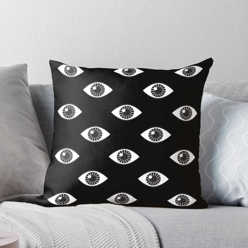 Close-up of a modern, minimalist black and white pillow with a hypnotic 'eyes wide open' pattern design.