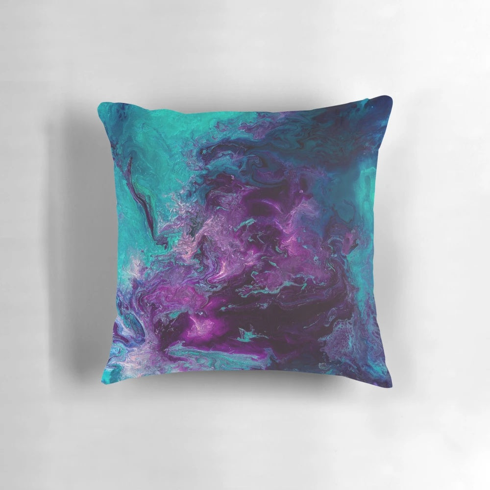 Closeup of a vibrant, abstract pillow featuring swirling shades of purple, teal, and turquoise, resembling a cosmic nebula.