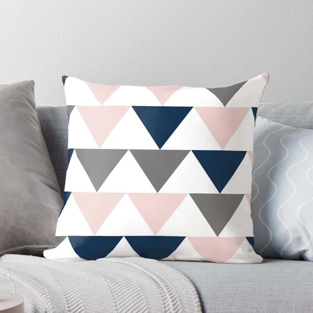 Minimalist geometric contemporary design pillow with a pattern of arrows in navy blue, charcoal grey, and blush pink on a white background