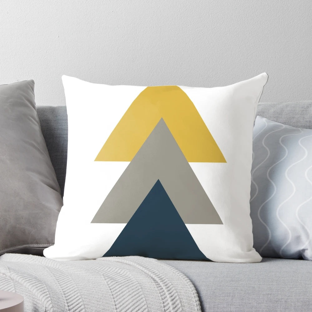 A minimalist, geometric pillow featuring a triangle pattern in light mustard yellow, white, grey, and navy blue.