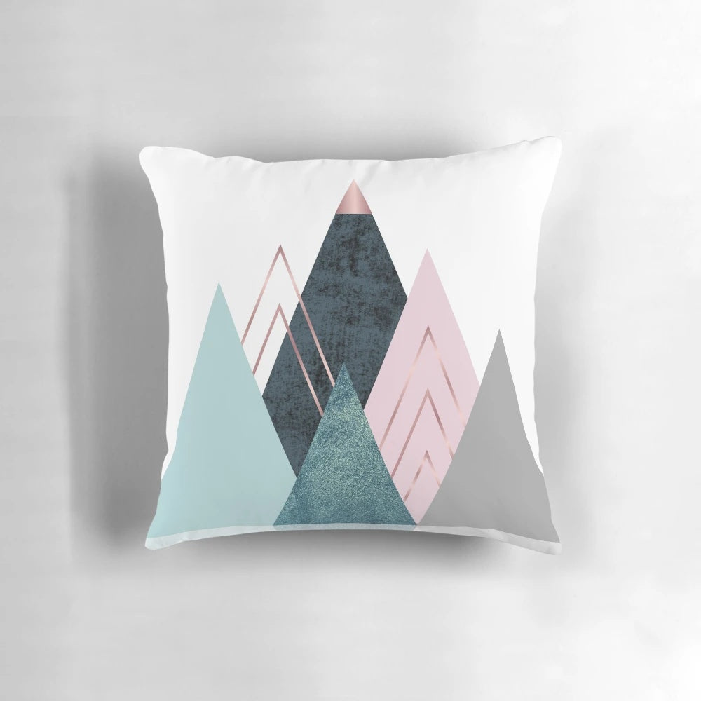 Minimalist mountain-inspired abstract art design on a pillow, featuring geometric shapes in pink, teal, and blue.