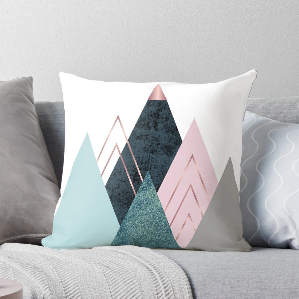 Minimalist mountain-inspired abstract art design on a pillow, featuring geometric shapes in pink, teal, and blue.