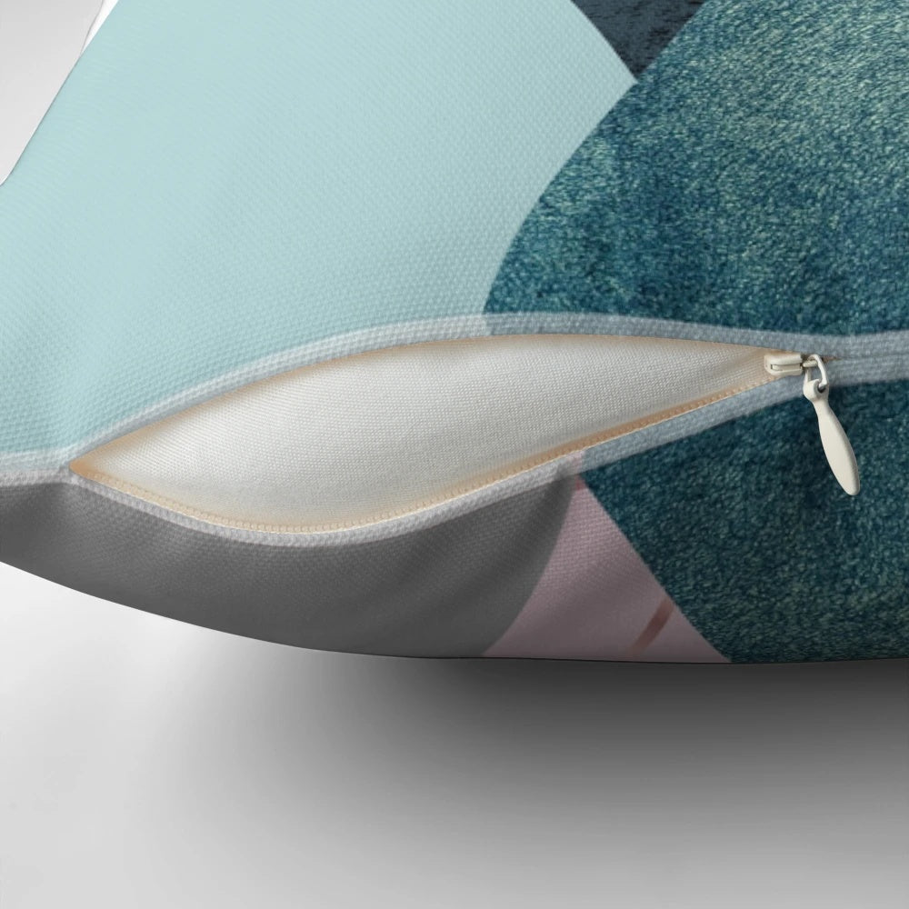 Minimalist mountain-inspired abstract art design on a pillow, featuring geometric shapes in pink, teal, and blue.