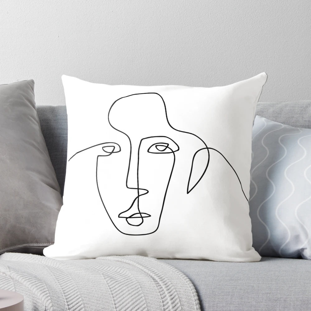 A black and white minimalist throw pillow featuring a simple, continuous line drawing of a face.