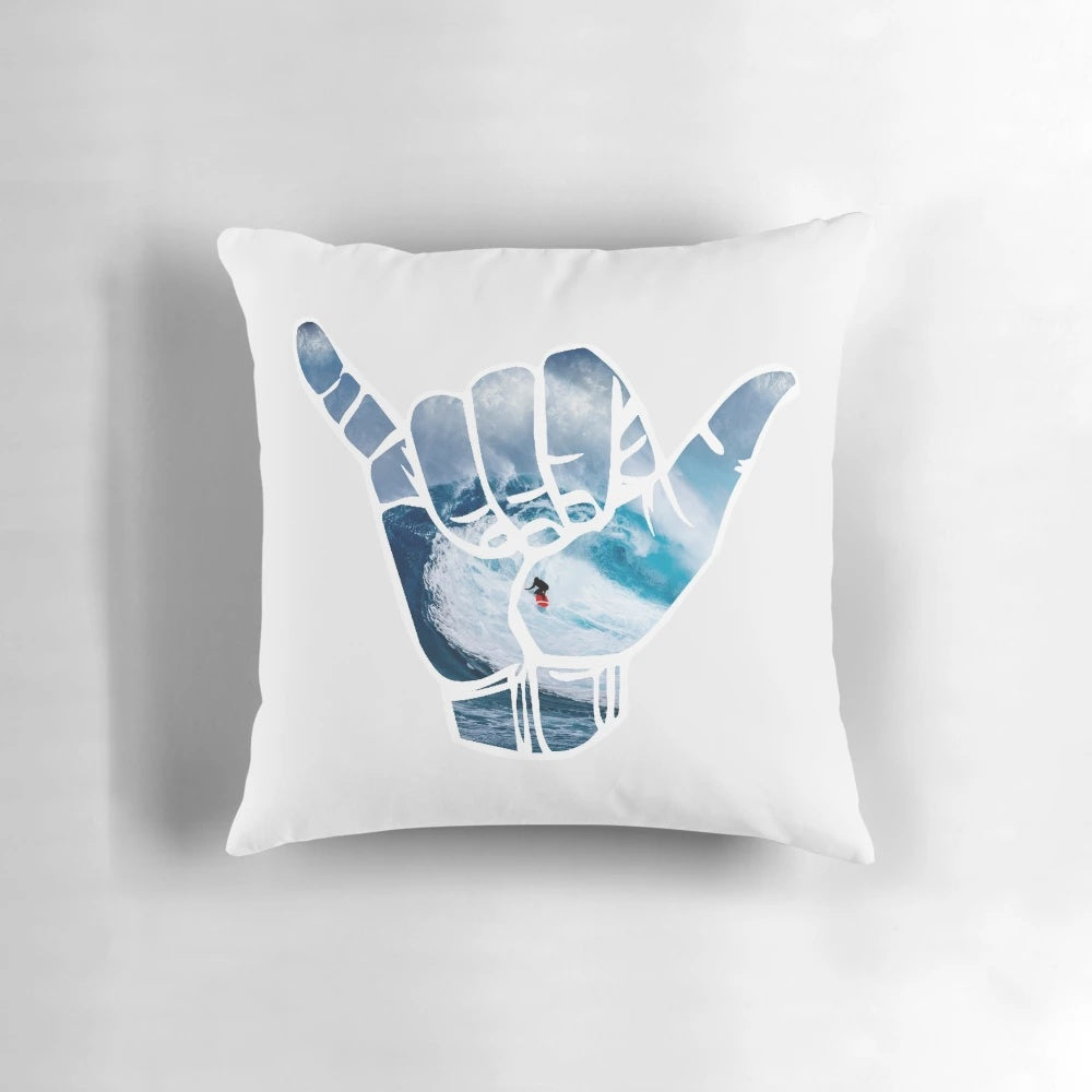 A white pillow with a simple, minimalist design featuring the "hang loose" hand symbol, surrounded by a space and star-filled background.