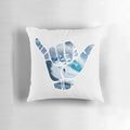 A white pillow with a simple, minimalist design featuring the "hang loose" hand symbol, surrounded by a space and star-filled background.