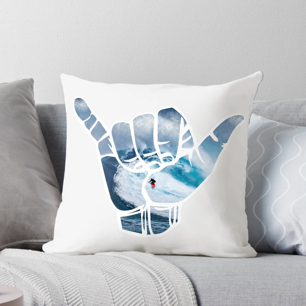 A white pillow with a simple, minimalist design featuring the "hang loose" hand symbol, surrounded by a space and star-filled background.