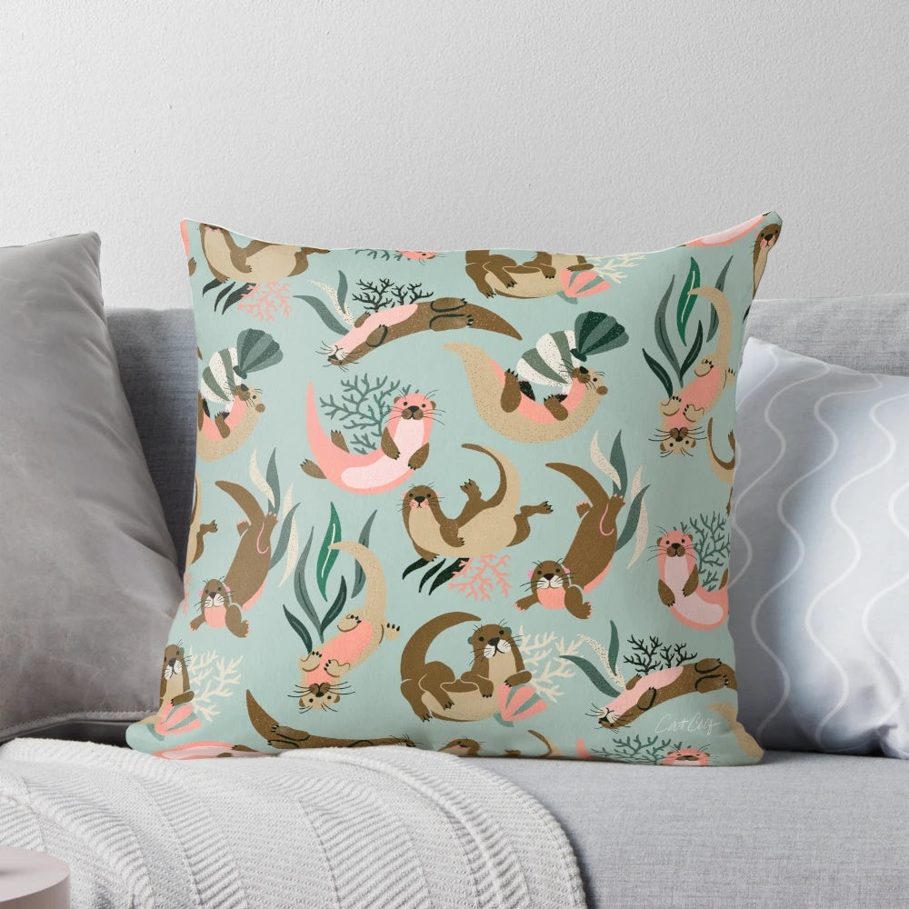 A mint-colored decorative pillow featuring adorable otters swimming in the ocean.
